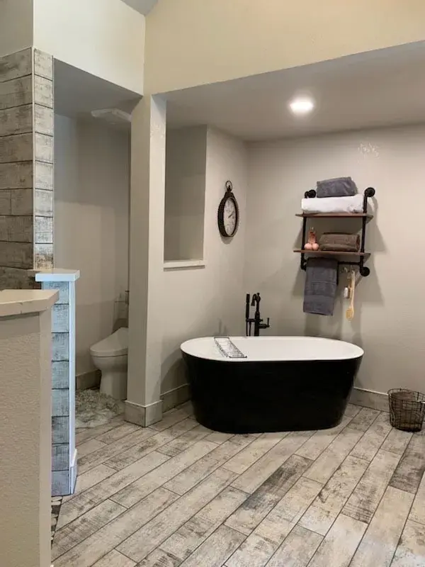 Bathroom project by Barron's Flooring & Home in Placerville, CA featuring Surface Art Wood-look tile planks, Black acrylic freestanding tub with Roman filler