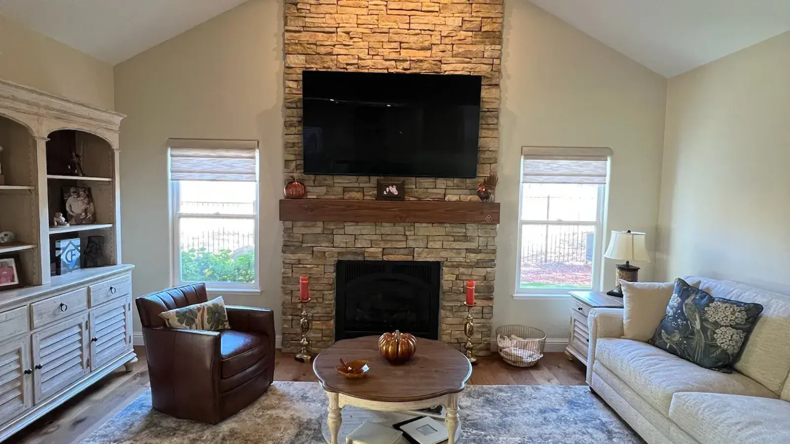 After: Living room re-floored with wood-look plank and a stacked-stone fireplace